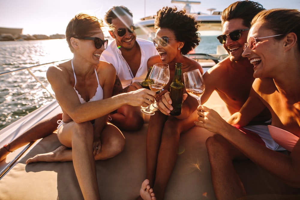 Eine Gruppe von Menschen an Bord eines Schiffes feiert, hat Spaß, trinkt etwas.