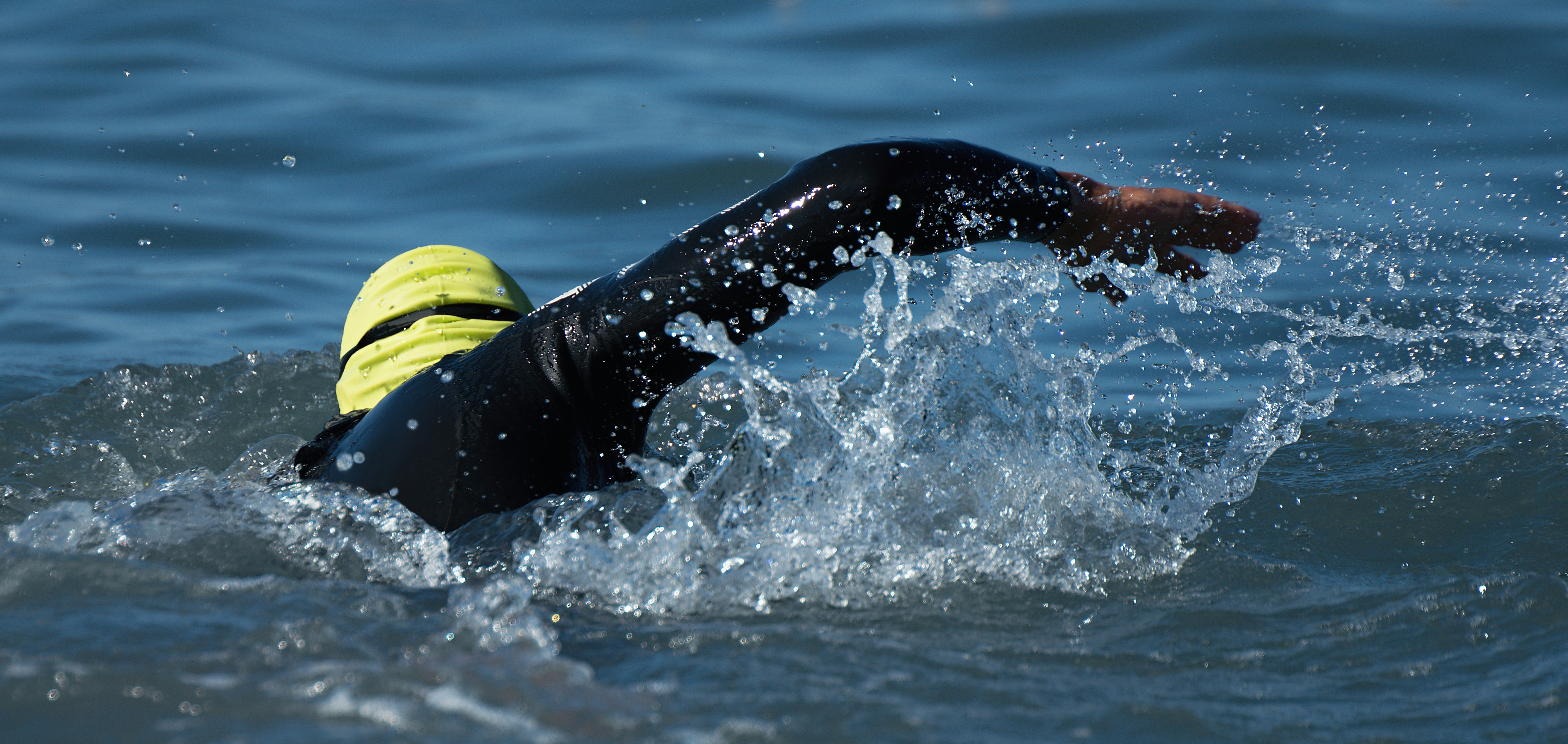 plavkyně v šedé čepici plave v ostrovní tyrkysové mořské vodě. Ženský sport v létě