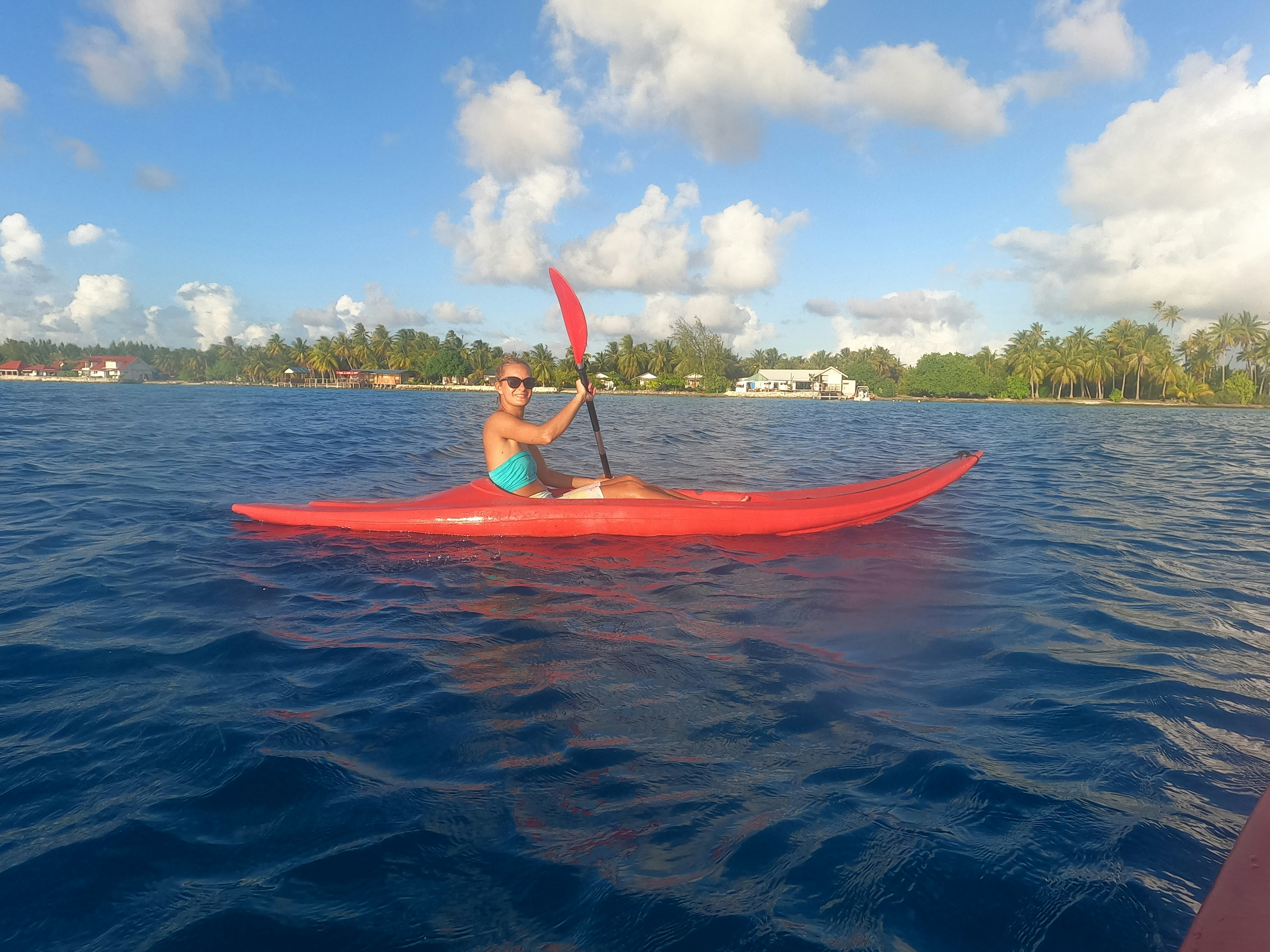 Una mujer en un kayak rojo en una bahía de la Polinesia Francesa.