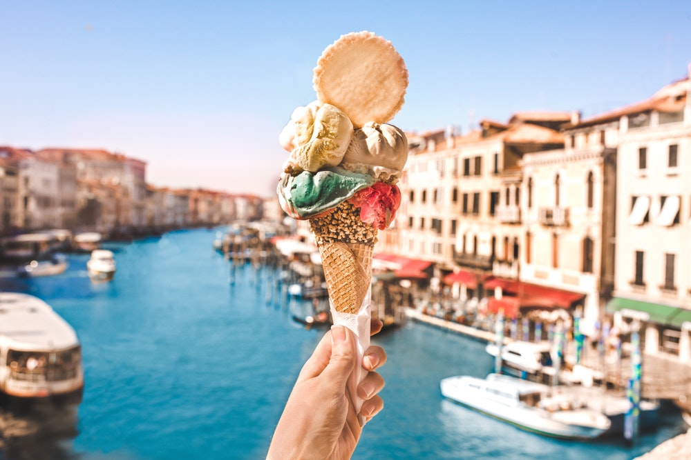 イタリア・ヴェネチアの美しい街で、水路や歴史的建造物の前でおいしいアイスクリームを食べる。